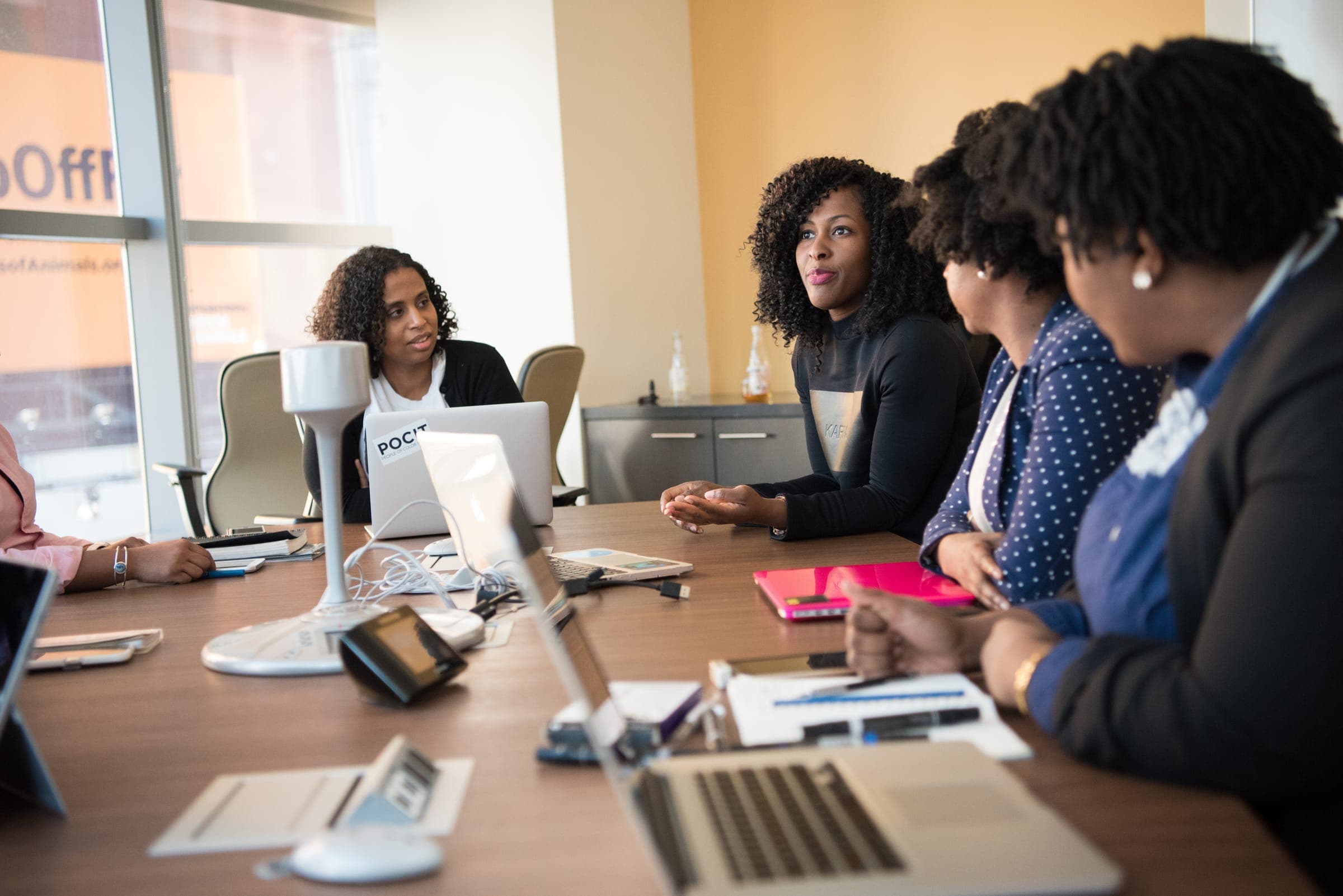 Colleagues around a meeting table with laptops